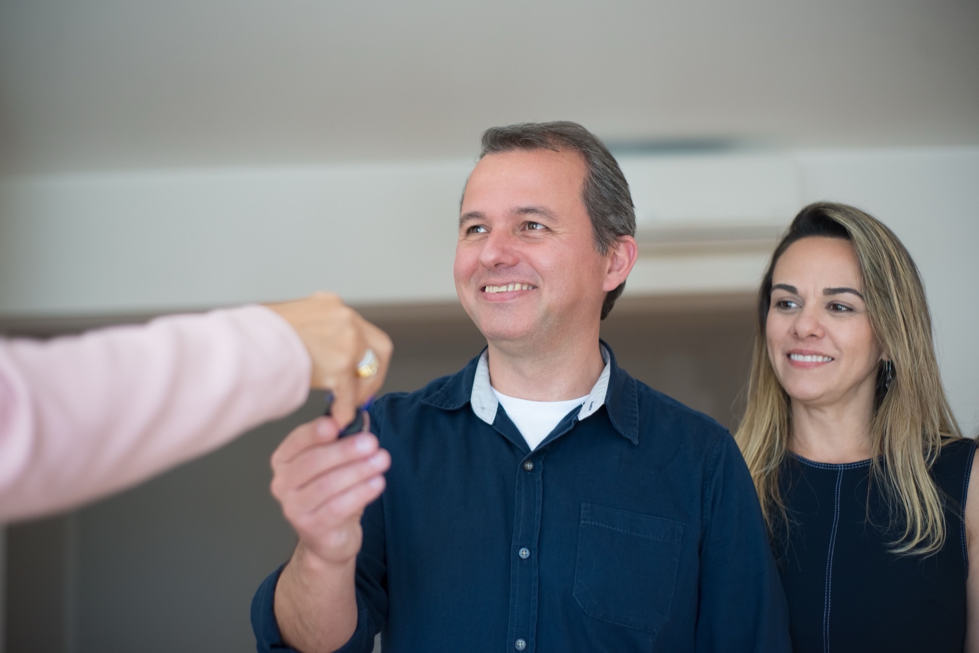 A first-time homebuyer holding keys to their new home with a smile
